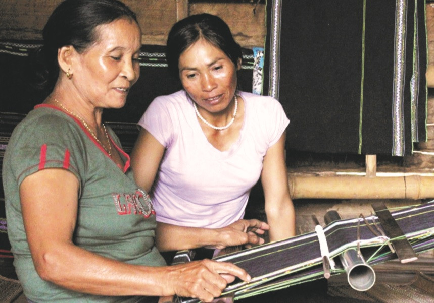 Bà H’Dleh Byă (bên trái) chỉ dạy cách dệt thổ cẩm cho con gái.