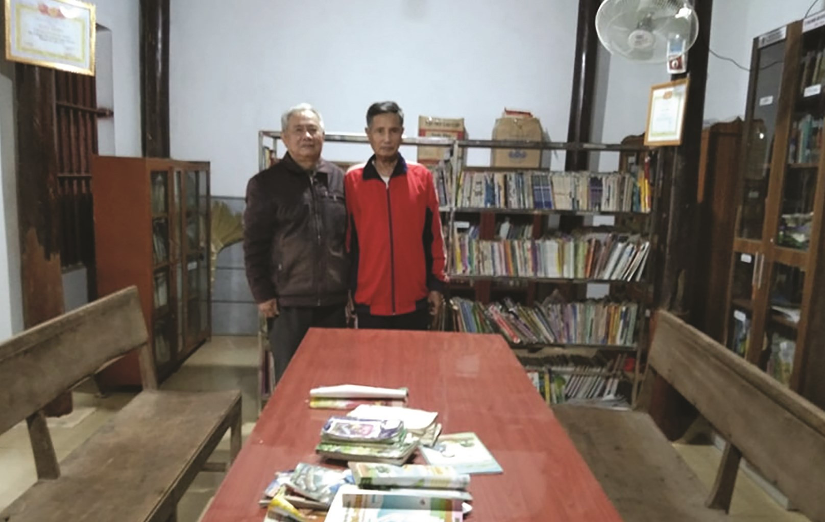 Ông Bùi Văn Thống (trái) trong thư viện của xóm do chính ông dành nhiều tâm huyết xây dựng.
