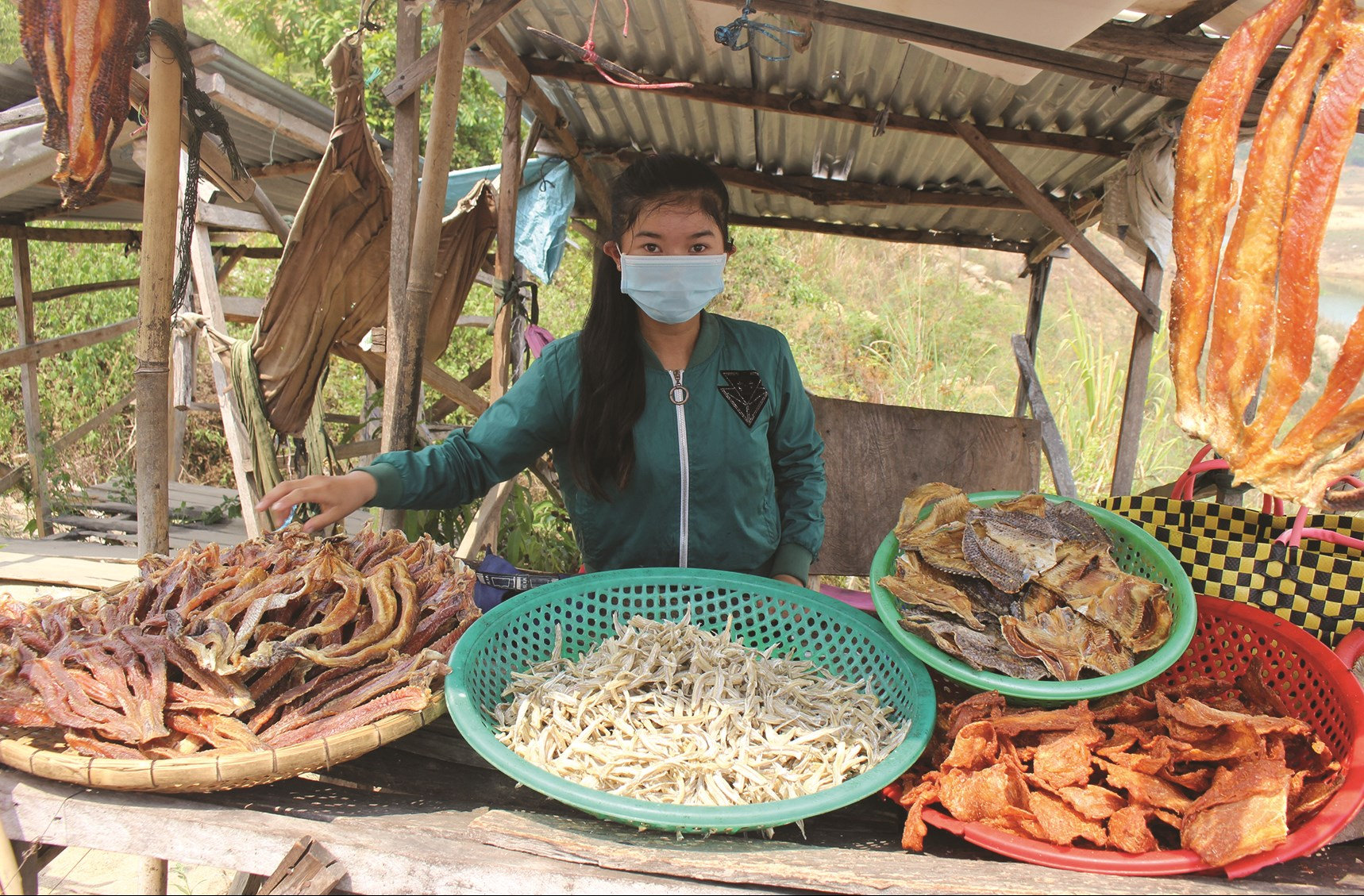 Trẻ em làng chài phụ gia đình bán khô cá trên chân cầu