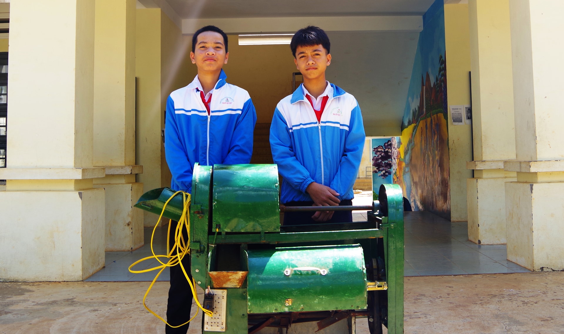 A Minh Khiêm (trái) và A Trường (phải) và chiếc máy cắt và trộn thức ăn trong chăn nuôi.