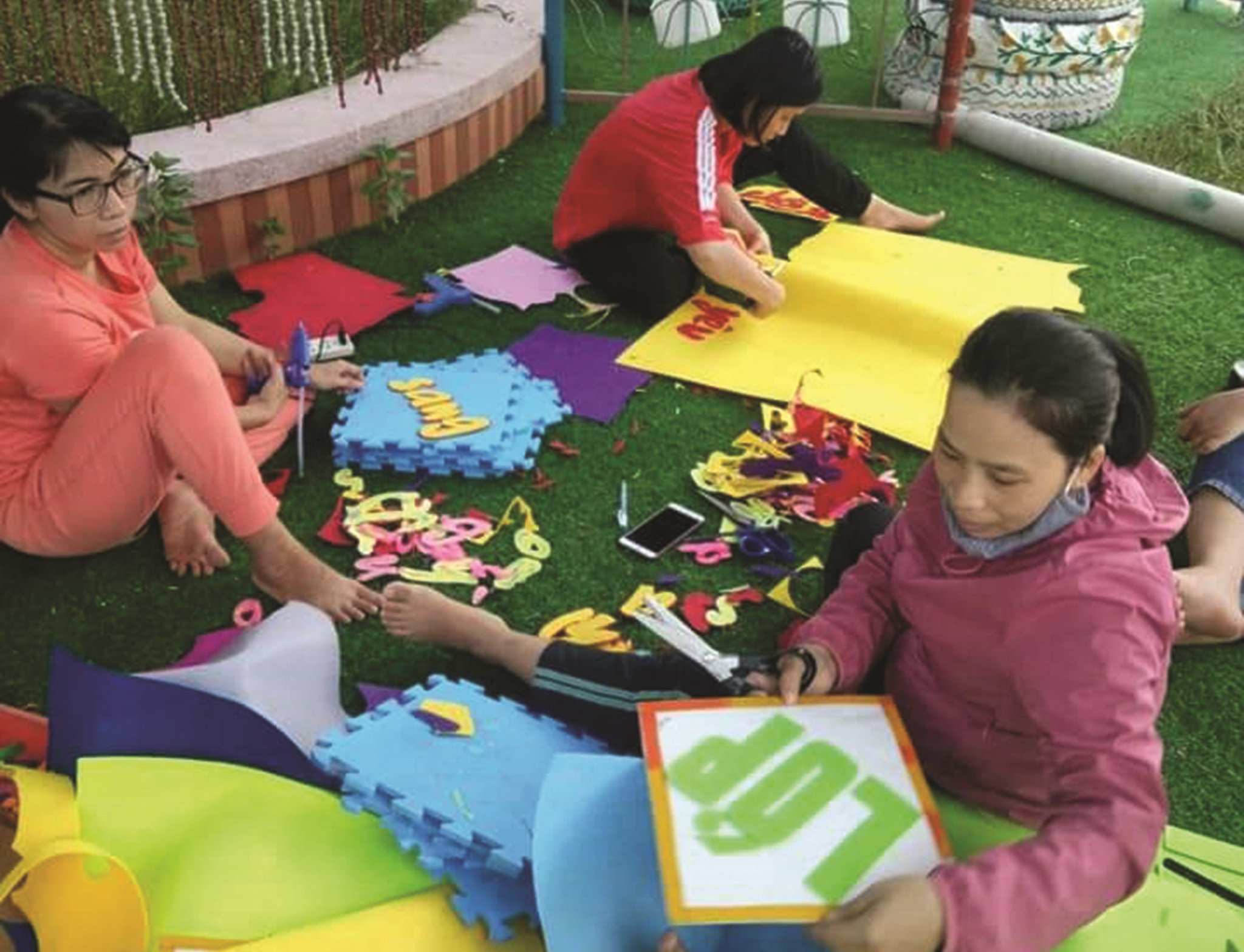 Các cô giáo Trường Mầm non Canh Vinh, huyện Vân Canh (Bình Định) đang cắt dán hình vẽ, con chữ để trang trí cho các góc chơi