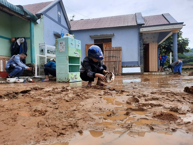 Người dân dọn dẹp bùn đất tại nhà sau lũ.