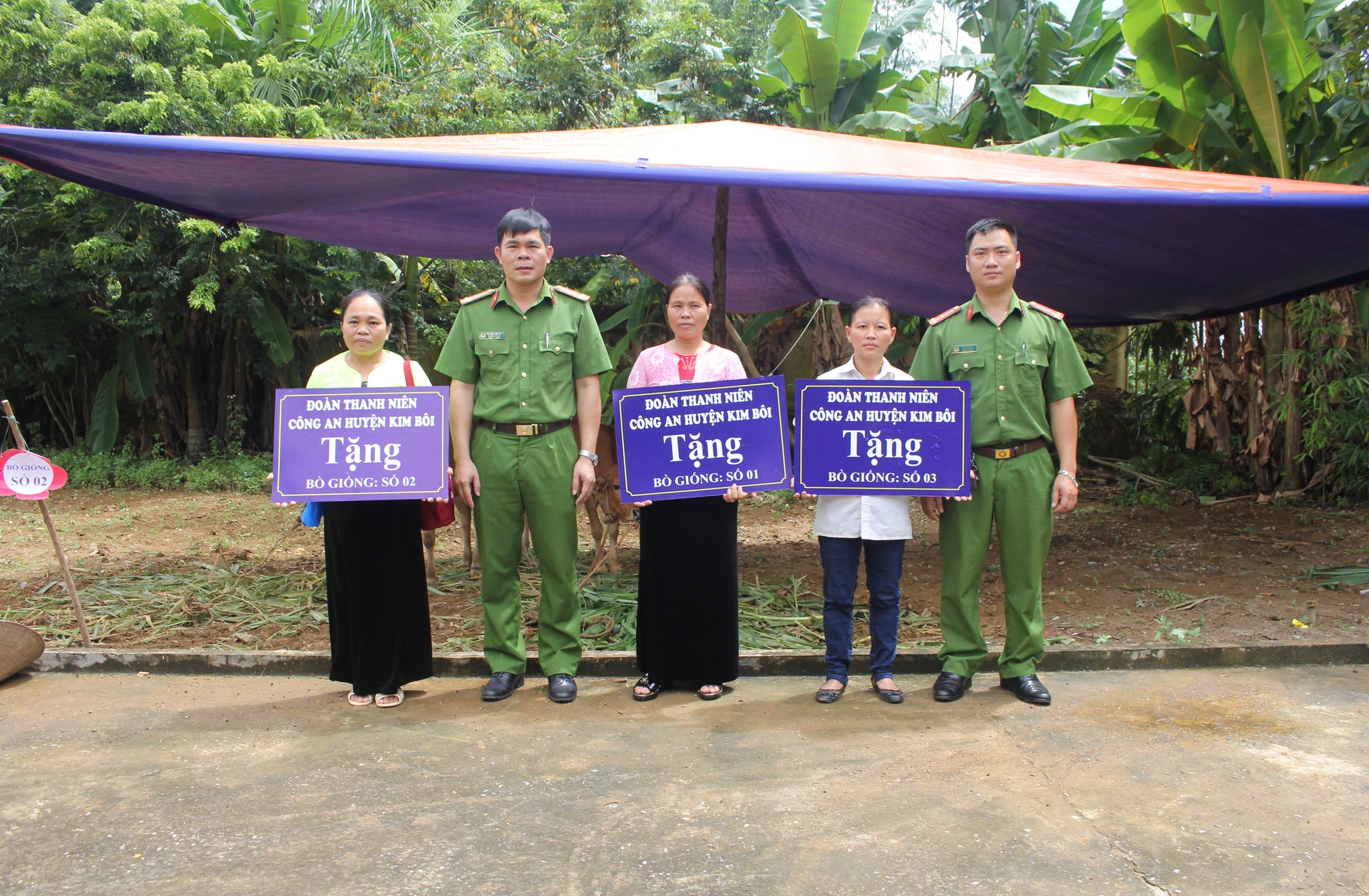 Thượng úy Bùi Đức Chí (ngoài cùng bên phải) trao tặng bò giống của Đoàn Thanh niên Công an huyện Kim Bôi cho các hộ đặc biệt khó khăn.