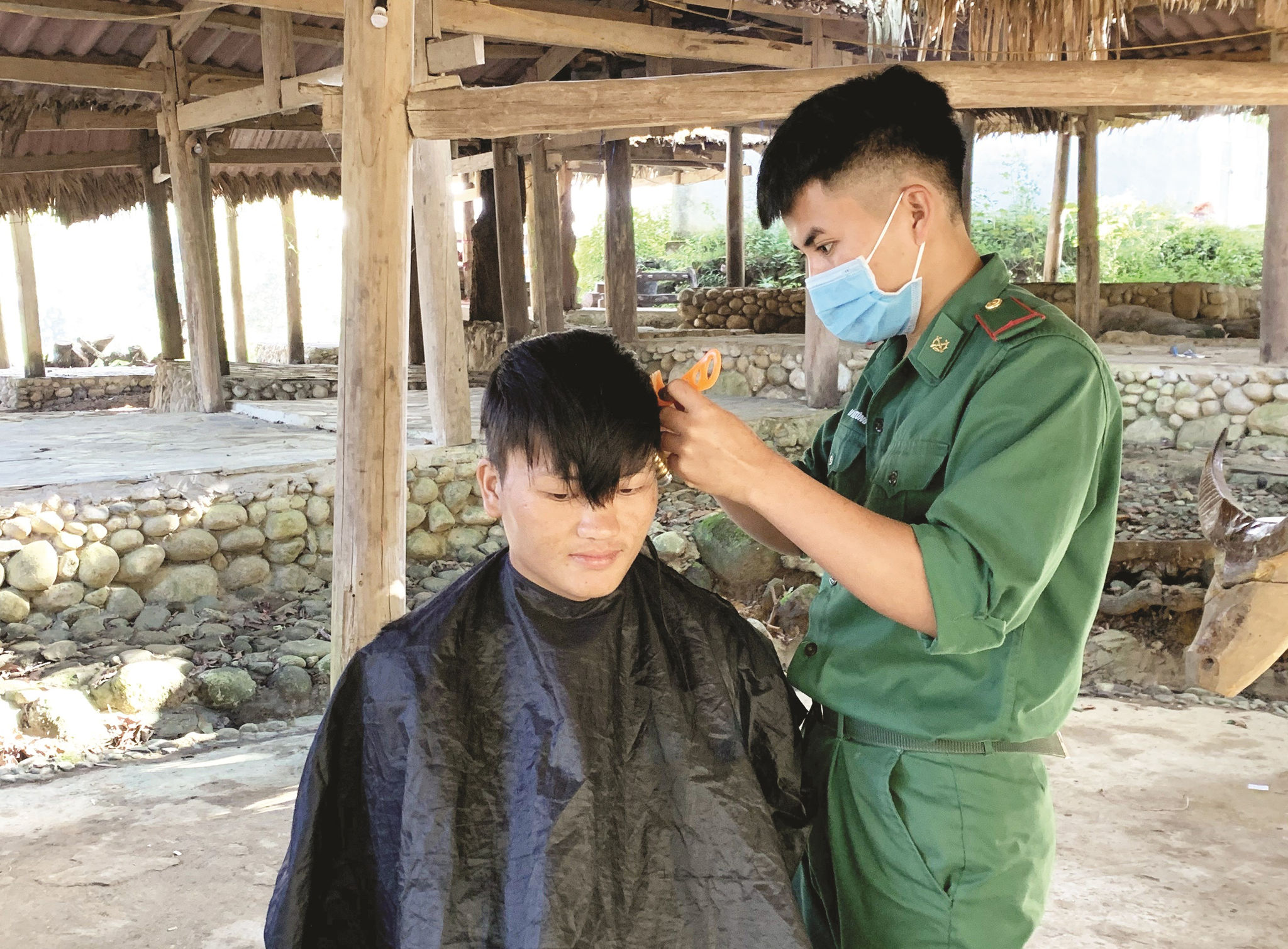 Tân binh Lò Văn Túng giúp người dân cắt tóc trong ngày sinh hoạt