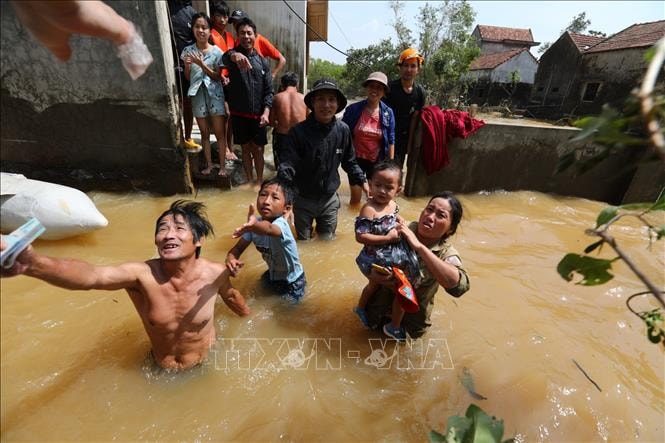 Người dân huyện Lệ Thủy (Quảng Bình) nhận tiền cứu trợ giữa dòng nước lũ, tháng 10/2020. Ảnh: Thành Đạt/TTXVN