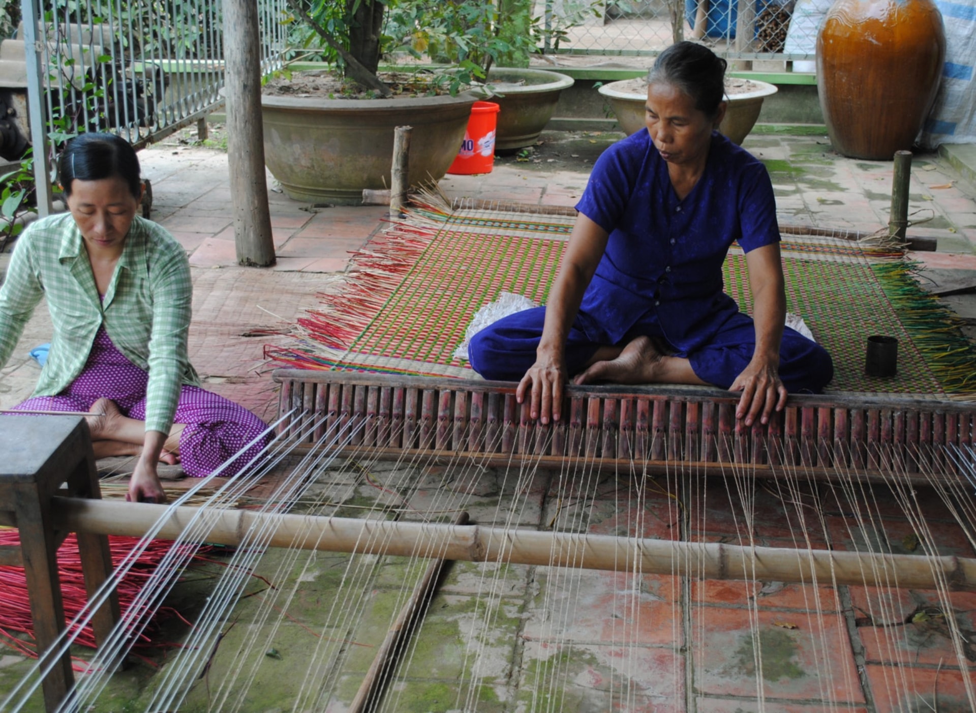 Bà Nguyễn Thị Ngọc Anh (bên phải) ở ấp An Trạch Tây, xã Thành Thới B đang thực hiện công đoạn dệt chiếu 