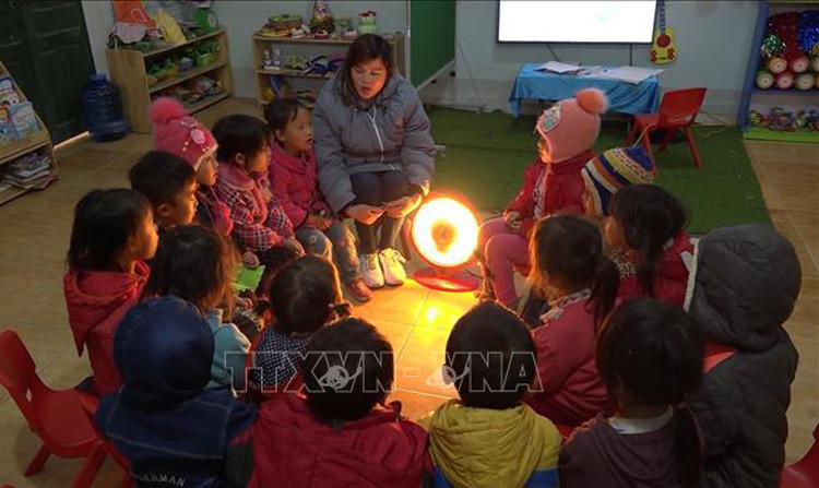 Cô và trò Trường  non thôn Cá Ha, xã Giàng Chu Phìn, huyện Mèo Vạc (Hà Giang) sưởi ấm bằng quạt điện. Ảnh: Nguyễn Chiến/TTXVN.