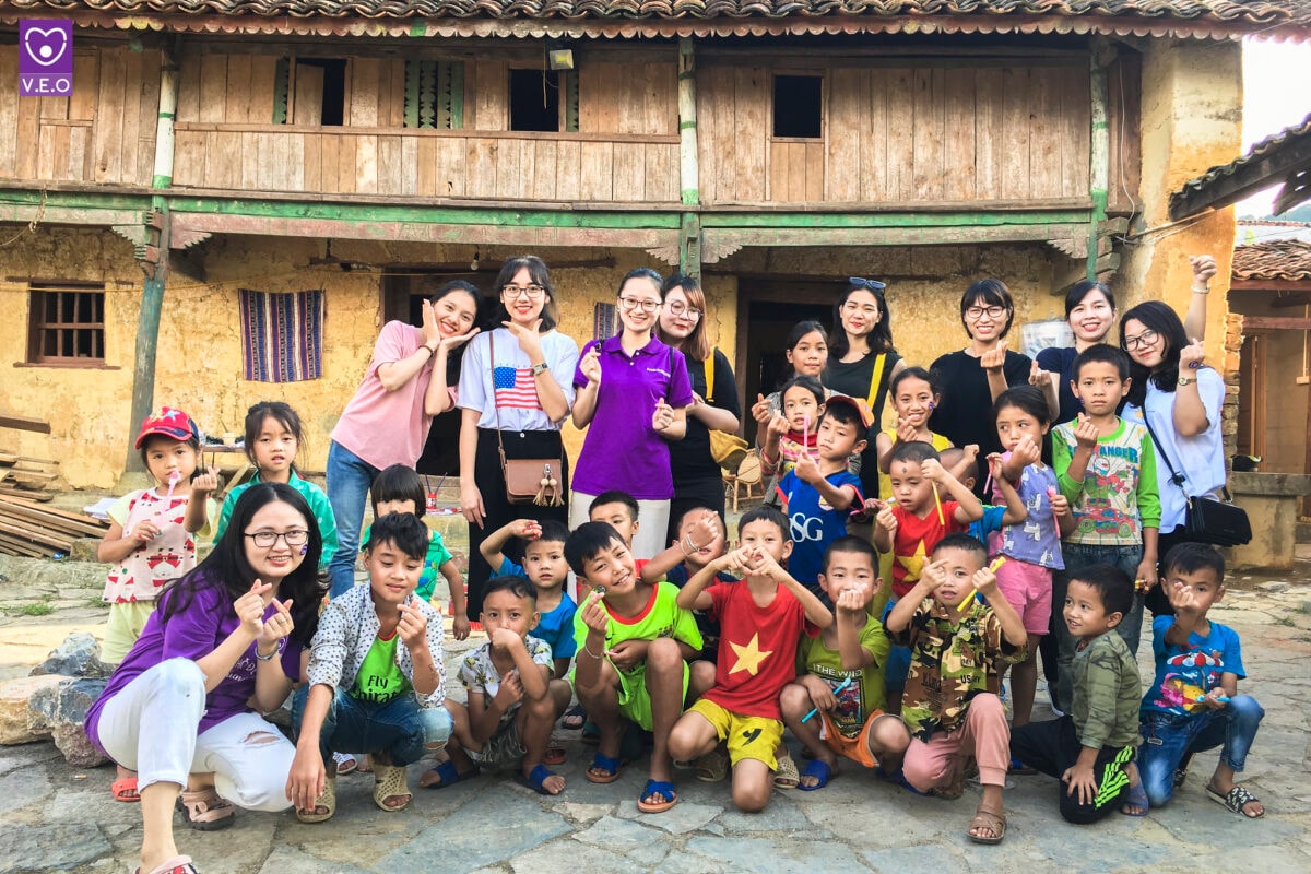 Khách du lịch chụp ảnh với trẻ em vùng cao tại một điểm du lịch cộng đồng ở Hà Giang.