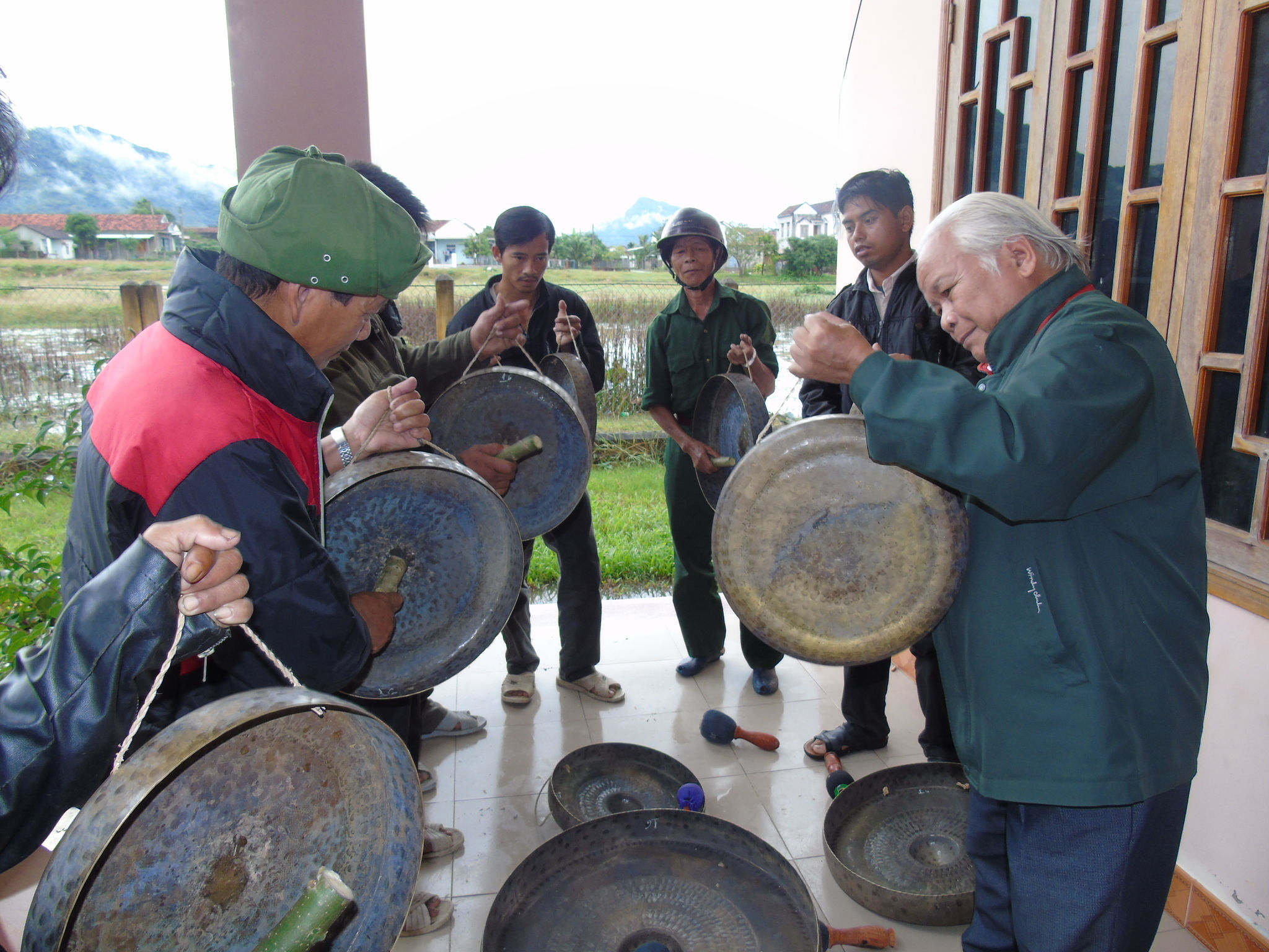 Nghệ nhân ưu tú Yang Danh (bên phải), chỉ cách đánh cồng chiêng cho đồng bào