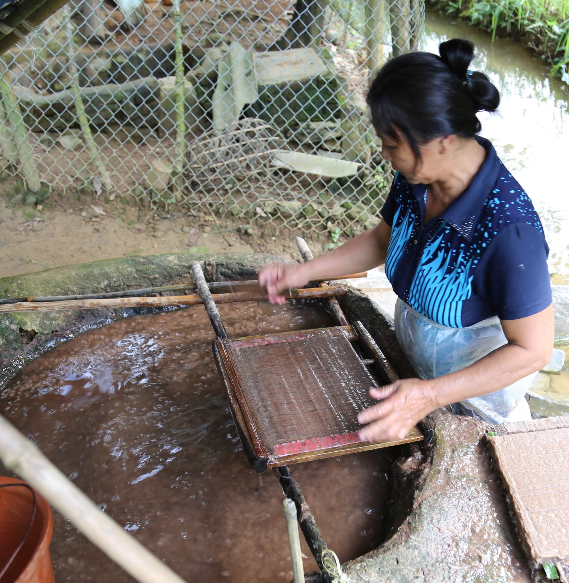 Bà Nông Thị Quyết đang lấy bột giấy lên khuôn.