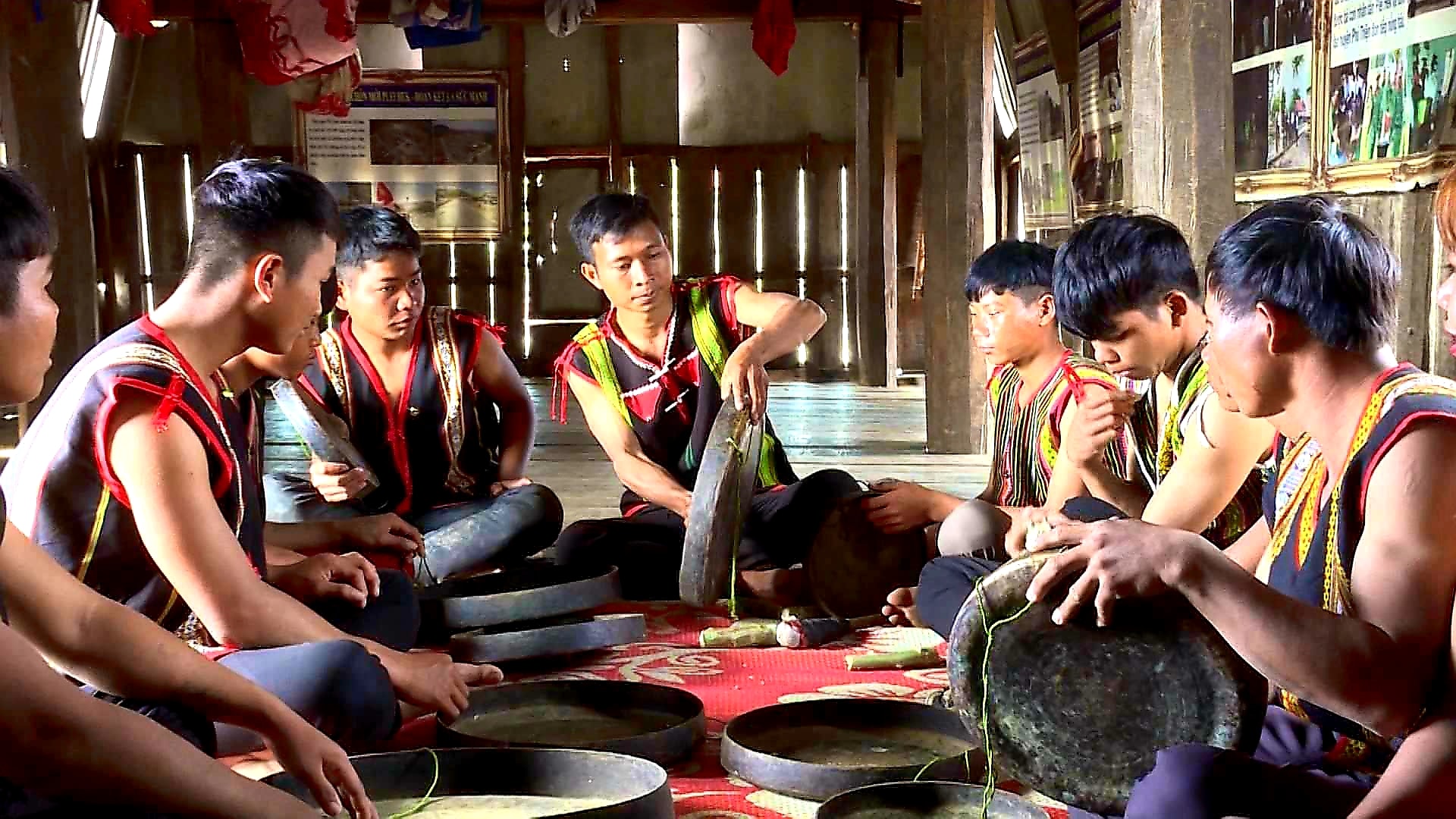 Rmah Mich (ở giữa) đang truyền dạy cồng chiêng cho lớp trẻ trong làng tại nhà rông