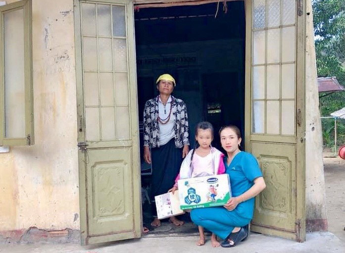 Chị Phan Thị Ánh Ly tặng quà của các nhà hảo tâm cho cháu Kim Na (thôn Gò Chè, xã Long Sơn) bị bệnh viêm màng não