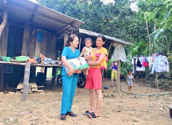 Chị Phan Thị Ánh Ly tặng quà của các nhà hảo tâm cho cháu Đinh Thị Mận, thôn An Thanh, xã Thanh An, huyện Minh Long