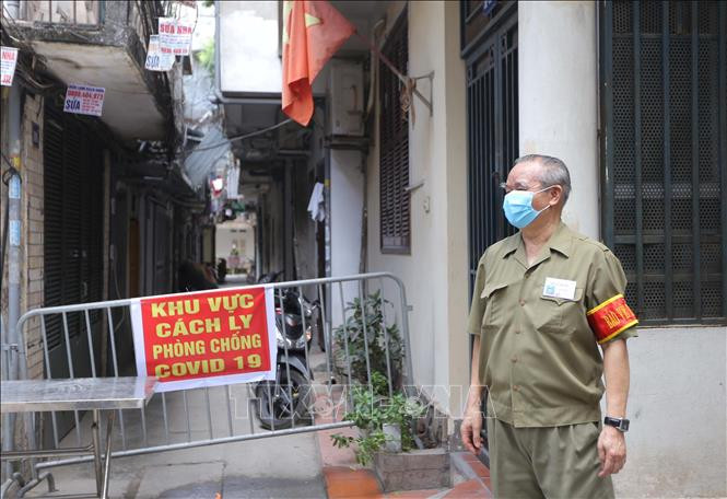 Lực lượng dân phòng hỗ trợ đảm bảo việc cách ly lối vào khu nhà có ca bệnh COVID-19. Ảnh: TTXVN.