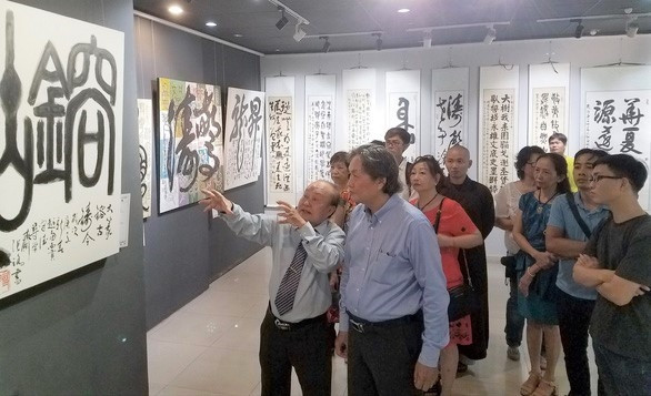 Họa sư Trương Lộ (trái) giới thiệu với công chúng tại triển lãm thư pháp của mình