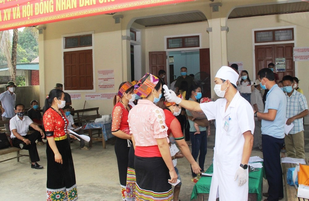 Cử tri ở Con Cuông, Nghệ An được kiểm tra thân nhiệt và sát khuẩn tay trước khi vào khu vực bỏ phiếu