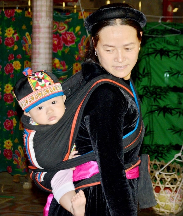 Người mẹ Tày địu em bé trên lưng (Ảnh: Báo Tuyên Quang)