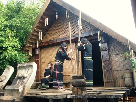 Phụ nữ Ê Đê giã gạo bên đầu hồi nhà dài truyền thống