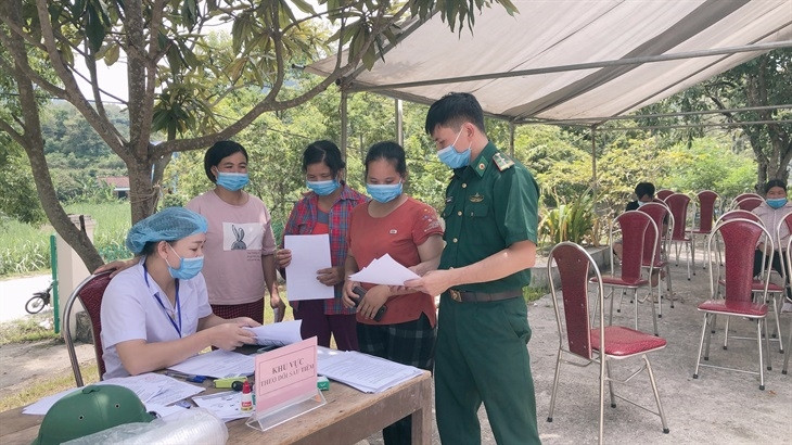 Cán bộ Đồn Biên phòng Thị Hoa và cán bộ y tế hướng dẫn các thủ tục cho người dân khi tiêm vaccine. Ảnh: Đức Linh