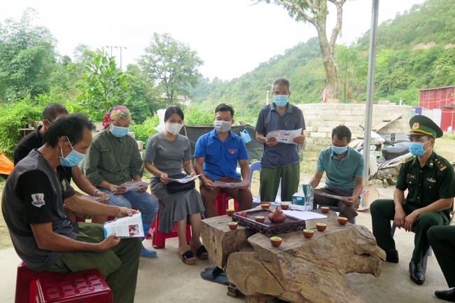 Ông Hứa Văn Dỉnh, Người có uy tín ở thôn Cốc Tòng (người đứng) cùng cán bộ, chiến sĩ Đồn Biên phòng Bảo Lâm phát tờ rơi tuyên truyền về phòng, chống dịch Covid-19