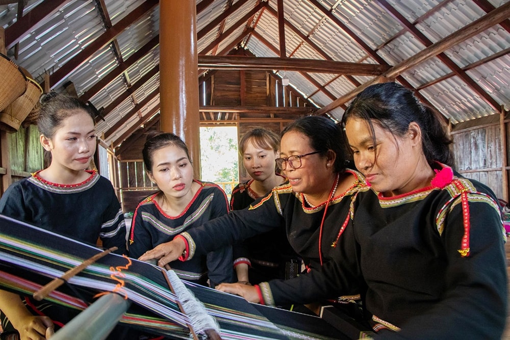 Bà H’Yam Bkrông (thứ hai từ phải sang) trao đổi với các thành viên của HTX Dệt thổ cẩm Tơng Bông ở buôn Tơng Jú, xã Ea Kao (TP. Buôn Ma Thuột) về cách dệt truyền thống