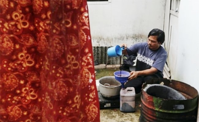 Anh Sodikin, thợ Batik đang rót dung dịch nhuộm màu chiết xuất từ “rừng ngập mặn” vào can