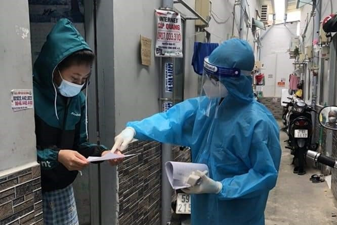 Nhân viên Trạm Y tế lưu động quận 7 (TP.HCM) hướng dẫn người nhà nhắc nhở F0 điều trị tại nơi cư trú cách dùng thuốc điều trị. Ảnh minh họa