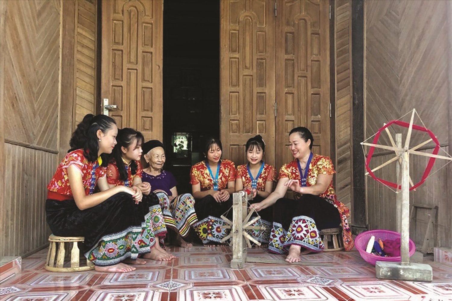 Các bà, các mẹ người Thái chỉ dạy cách quay sợi cho lớp trẻ.