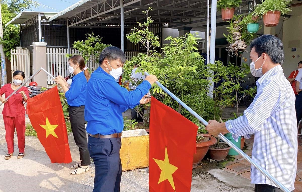 Các đoàn viên thanh niên hỗ trợ người dân treo cờ Tổ quốc