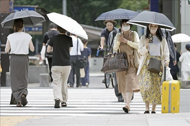Người dân che ô tránh nắng khi di chuyển trên đường phố tại Nagoya, Nhật Bản, ngày 27/6/2022. Ảnh: Kyodo/ TTXVN Người dân che ô tránh nắng khi di chuyển trên đường phố tại Nagoya, Nhật Bản, ngày 27/6/2022. Ảnh: Kyodo/ TTXVN