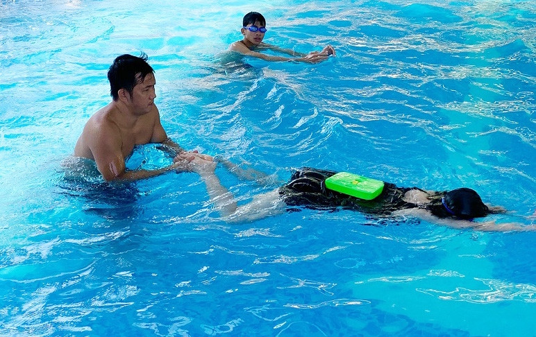 Thầy giáo đang hướng dẫn học sinh các kỹ thuật, kỹ năng trong khi bơi