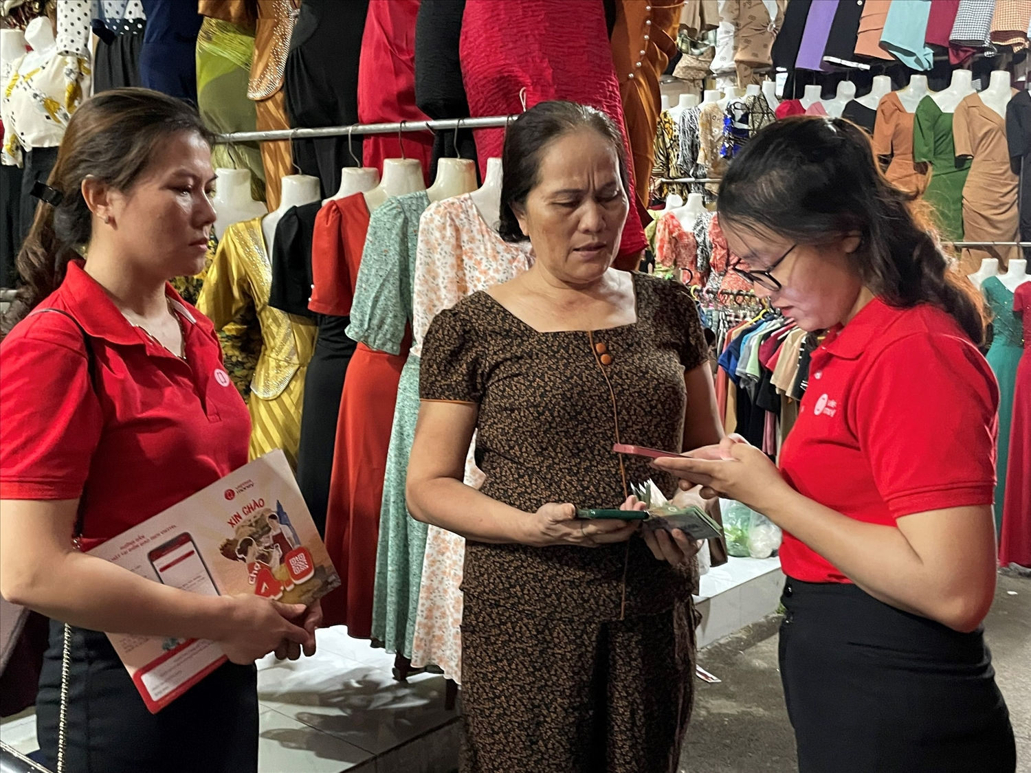 Nhân viên Viettel Bình Phước hướng dẫn tiểu thương Chợ Đồng Xoài, Tp. Đồng Xoài cài đặt và sử dụng cài đặt ứng dụng Viettel Money để thuận tiện cho việc thanh toán không dùng tiền mặt