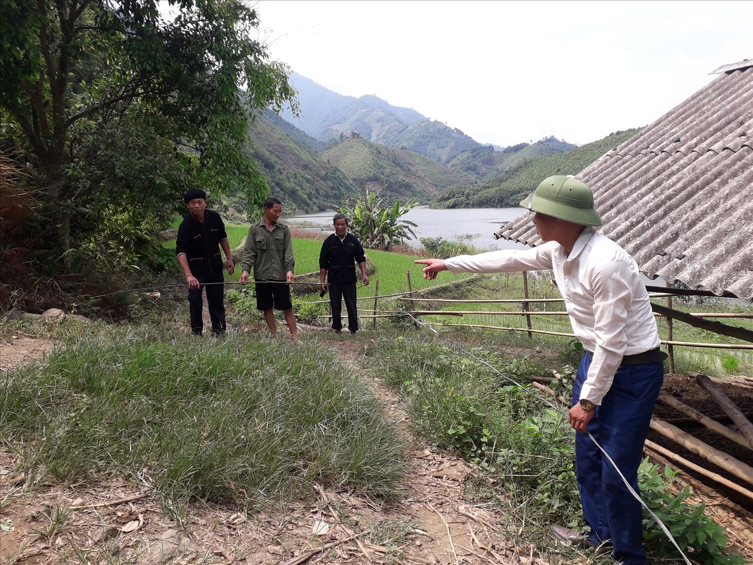Phó Chủ tịch UBND xã Mỏ Vàng Đặng Tòn Lây (áo trắng) và Người có uy tín Phùng Vinh Minh, La Tài Quan cùng hộ dân ông Ly Seo Chuy đo phần diện tích đất con đường sẽ đi qua