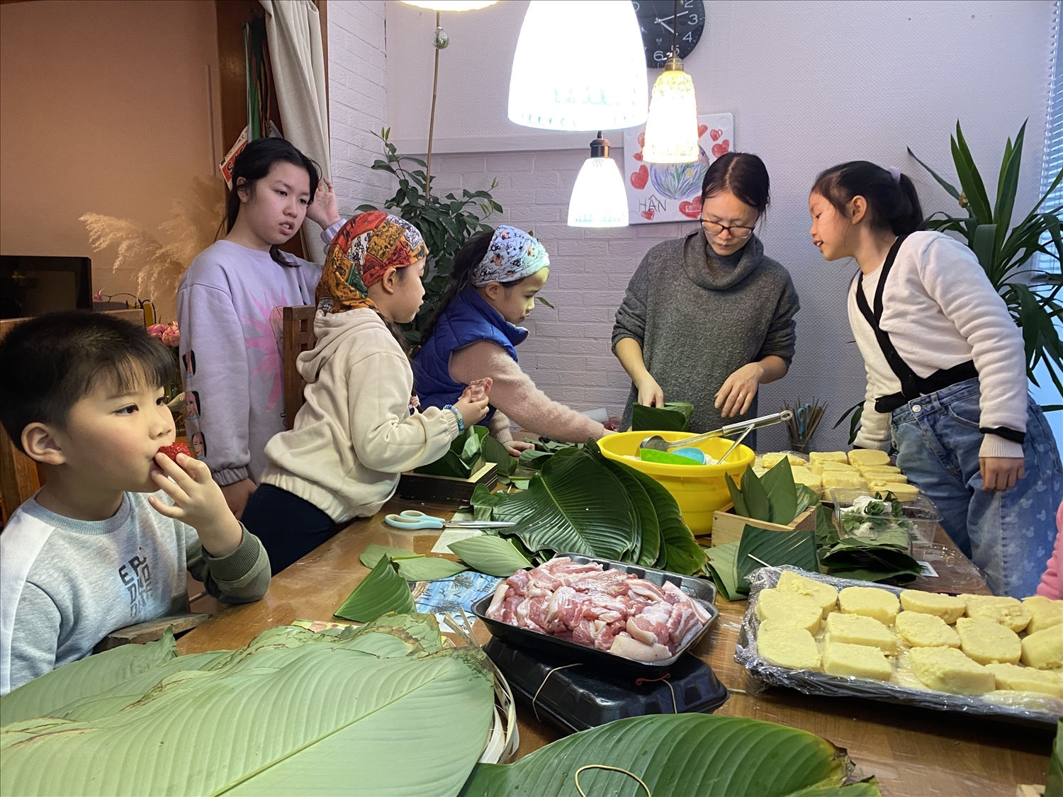 Các cháu nhỏ tại Bỉ tập trung học cách gói bánh chưng. (Ảnh: Thành Long/TTXVN)