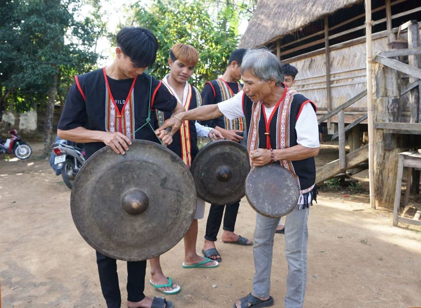Ông A De điều chỉnh từng động tác đánh chiêng cho lớp trẻ. Ảnh: TT Ông A De điều chỉnh từng động tác đánh chiêng cho lớp trẻ. Ảnh: TT