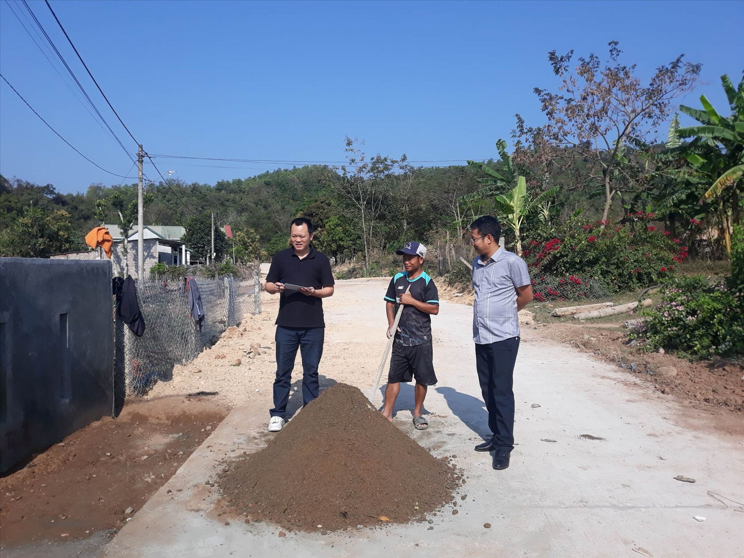 Chia sẻ niềm vui khi có đường mới xong, anh Hồ Văn Hiệp (đứng giữa) lại thoăn thoát trộn mẻ hồ đang giở để làm vỉa hè trước nhà mình cho đẹp cùng đường liên bản
