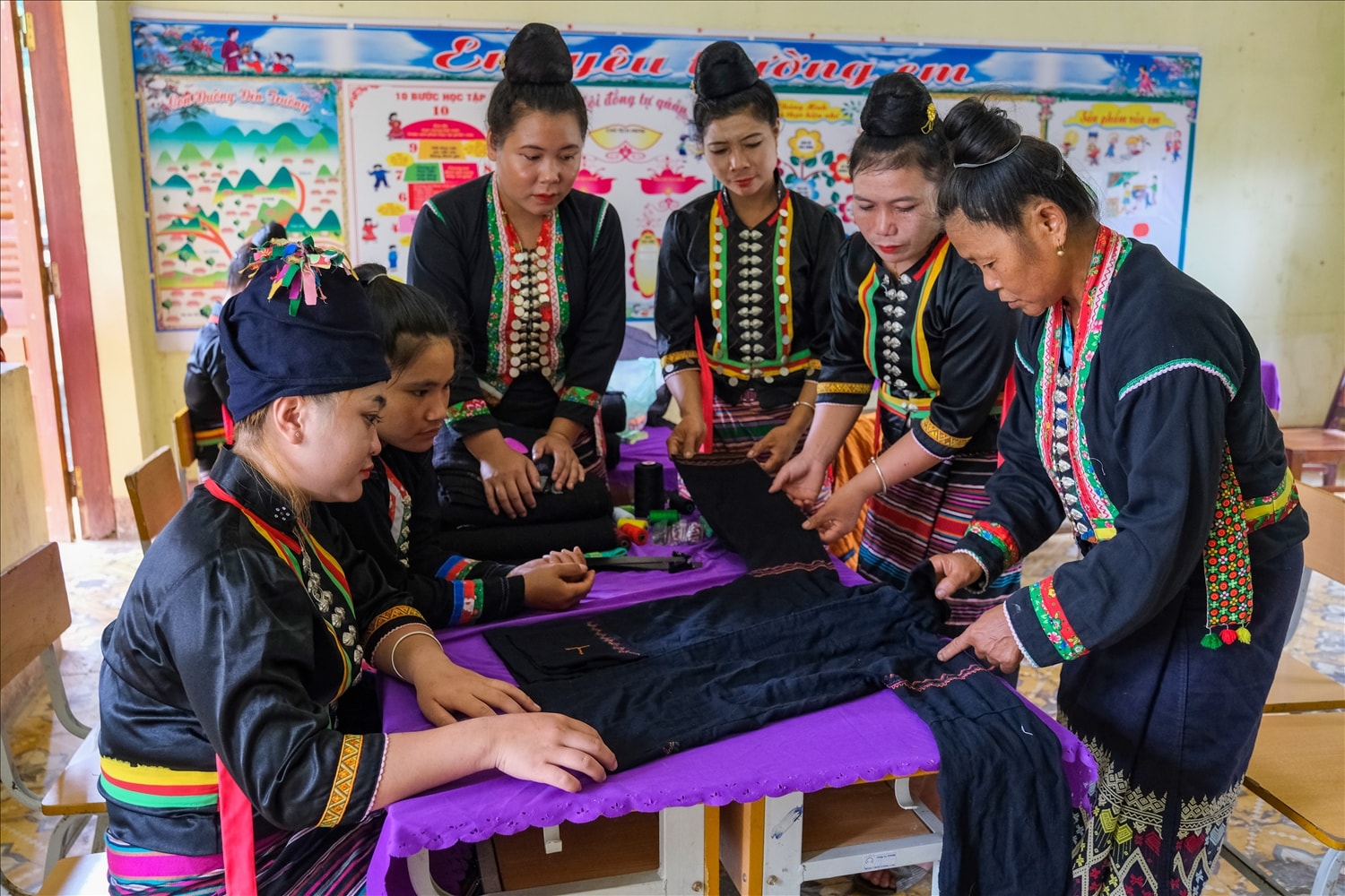 Những người lớn tuổi truyền dạy nghề cắt may trang phục truyền thống cho thế hệ sau.