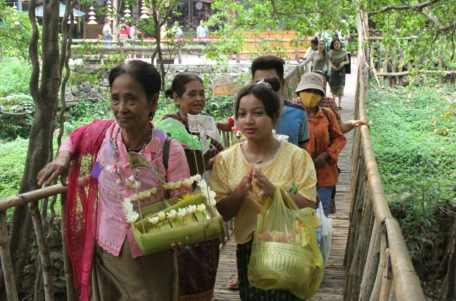 Từ sáng sớm, cộng đồng người Lào đang cư trú trên địa bàn xã Krông Na chỉnh tề trong trang phục truyền thống tấp nập đổ về đảo Ây Nô (trên sông Sêrêpốk, thuộc Trung tâm Du lịch cầu treo Buôn Đôn). Phụ nữ lớn tuổi chuẩn bị những bè hoa đăng, các cô gái Lào không quên cài trên đầu bông hoa chăm pa trắng ngần đến lễ hội.