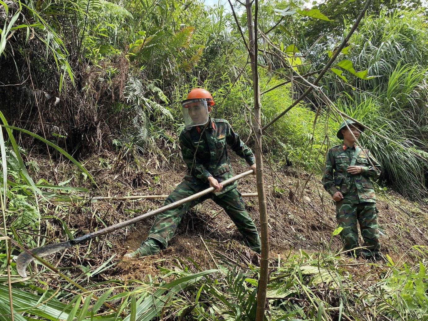 Giữa thời tiết oi nóng, những tiếng ve rừng kêu inh tai, những người lính thận trọng phát quang từng mét vuông đất để đồng đội có thể sử dụng máy dò mìn rà phá kỹ càng từng tấc đất, không để sót một tín hiệu nào.