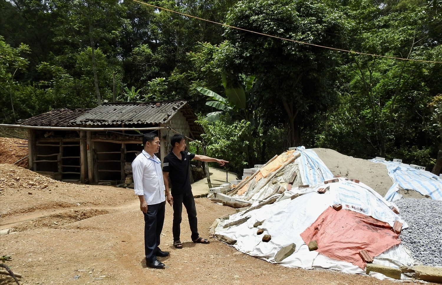 Bí thư Đảng uỷ xã Vân Thuỷ, huyện Chi Lăng - Hoàng Văn Phách (áo trắng) đi kiểm tra và động viên các gia đình được hỗ trợ  xây dựng nhà ở 
