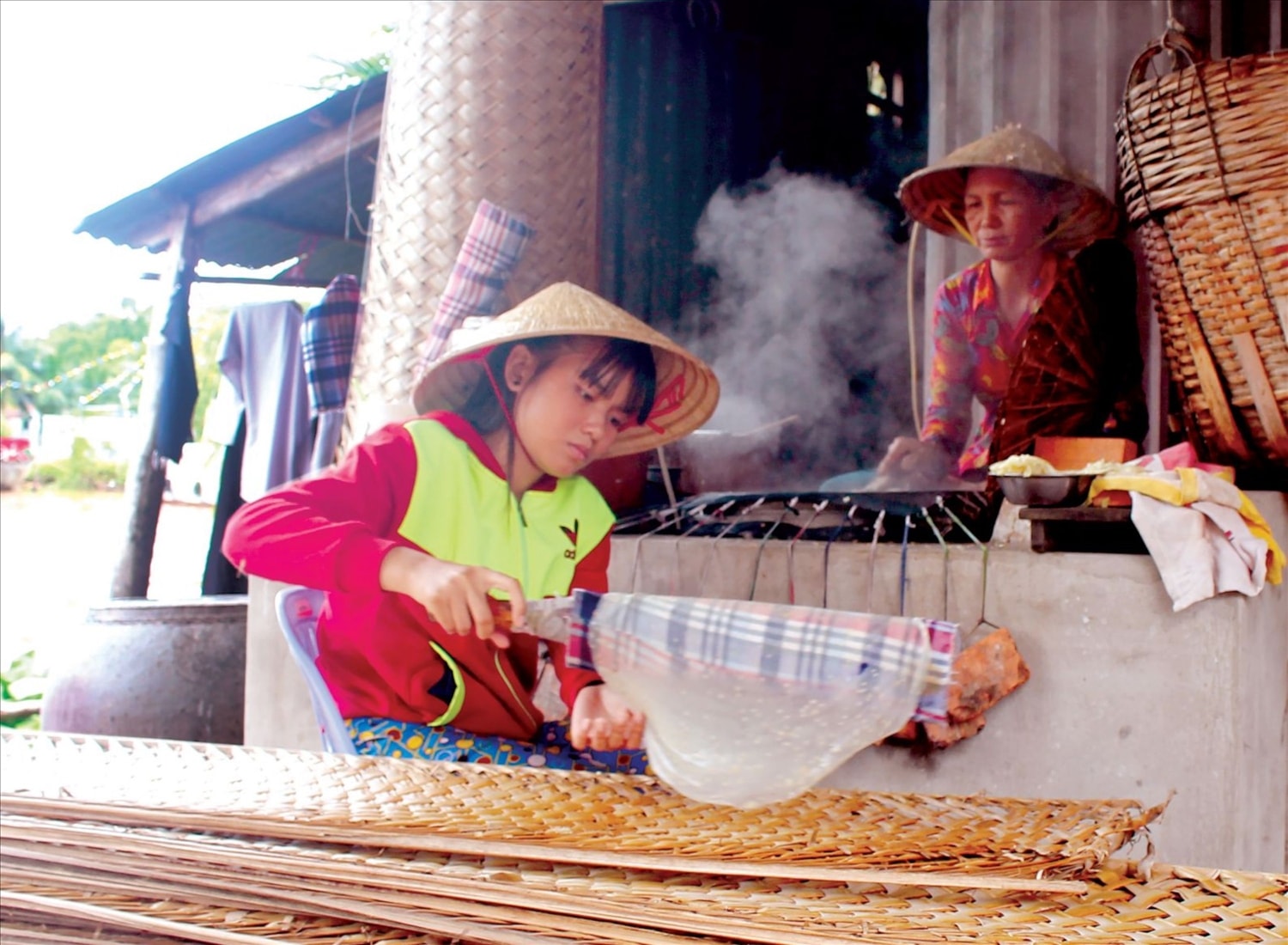 Bà Trần Thị Tuyết Mai và con gái ở ấp Tân Thạnh, xã Lục Sĩ Thành, thành viên HXT tỉ mỉ tráng từng chiếc bánh. 