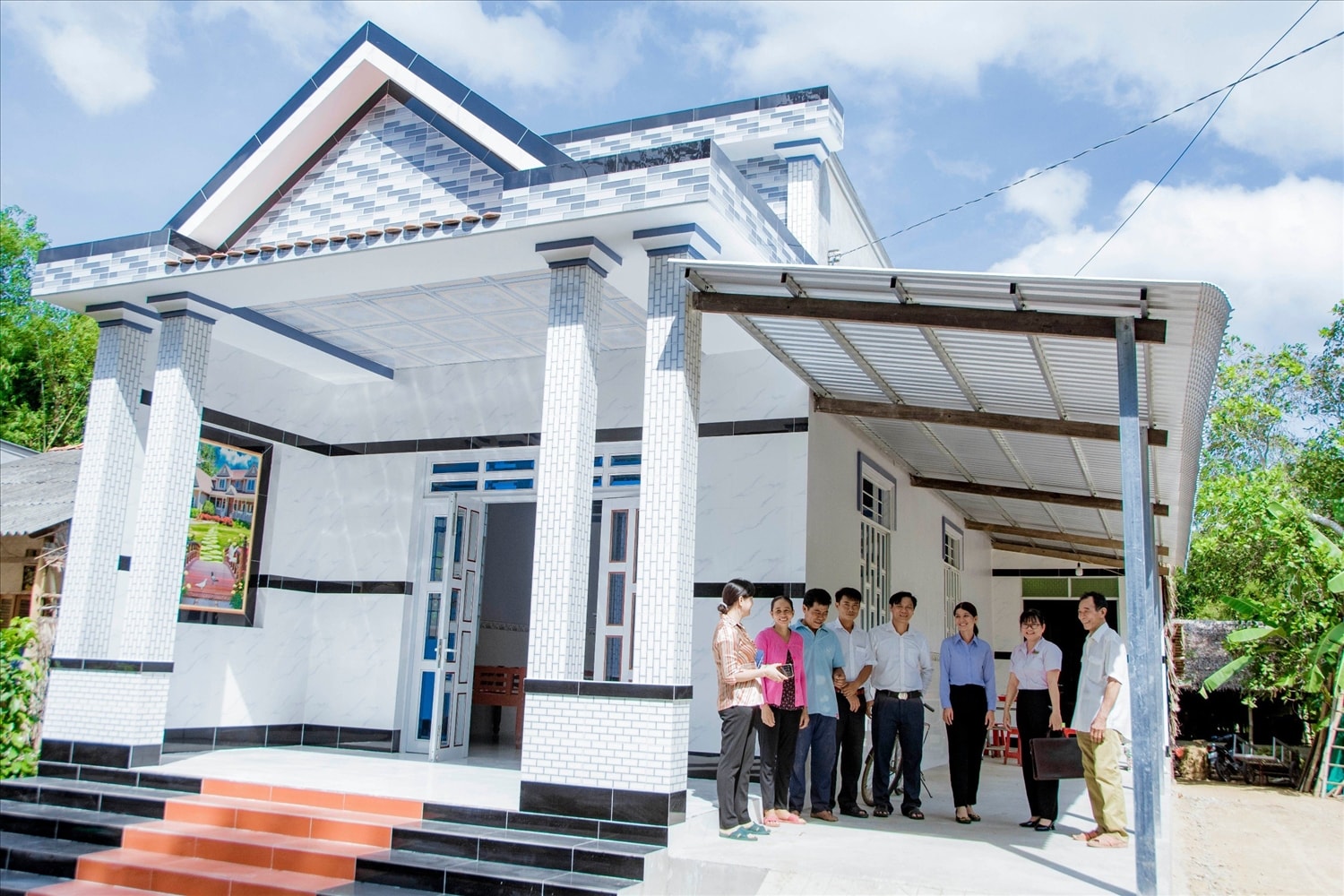 Vợ chồng anh Thạch Tiên ( người thứ 2 và 3 bên trái qua) ngụ ấp Mộc Anh, xã Lưu Nghiệp Anh, huyện Trà Cú ( Trà Vinh) cùng đoàn công tác Phòng giao dịch NHCSXH  và cán bộ xã  bên căn nhà mới 