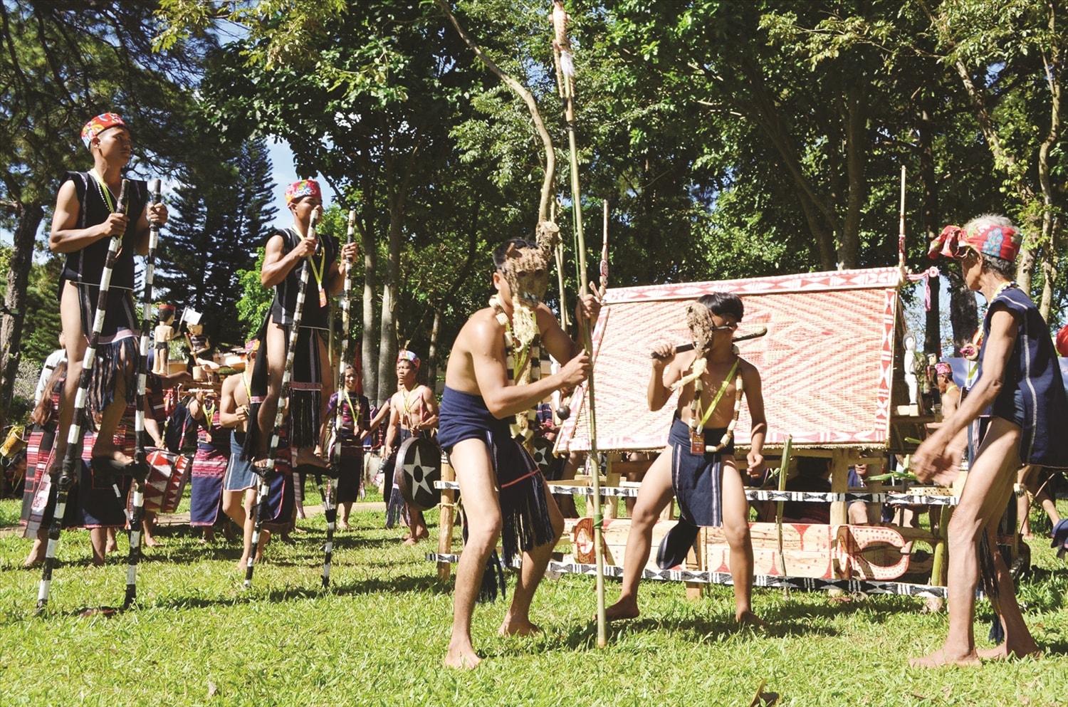 Người hóa trang và dàn cồng chiêng đi quanh khu nhà mả trong Lễ bỏ mả Người hóa trang và dàn cồng chiêng đi quanh khu nhà mả trong Lễ bỏ mả