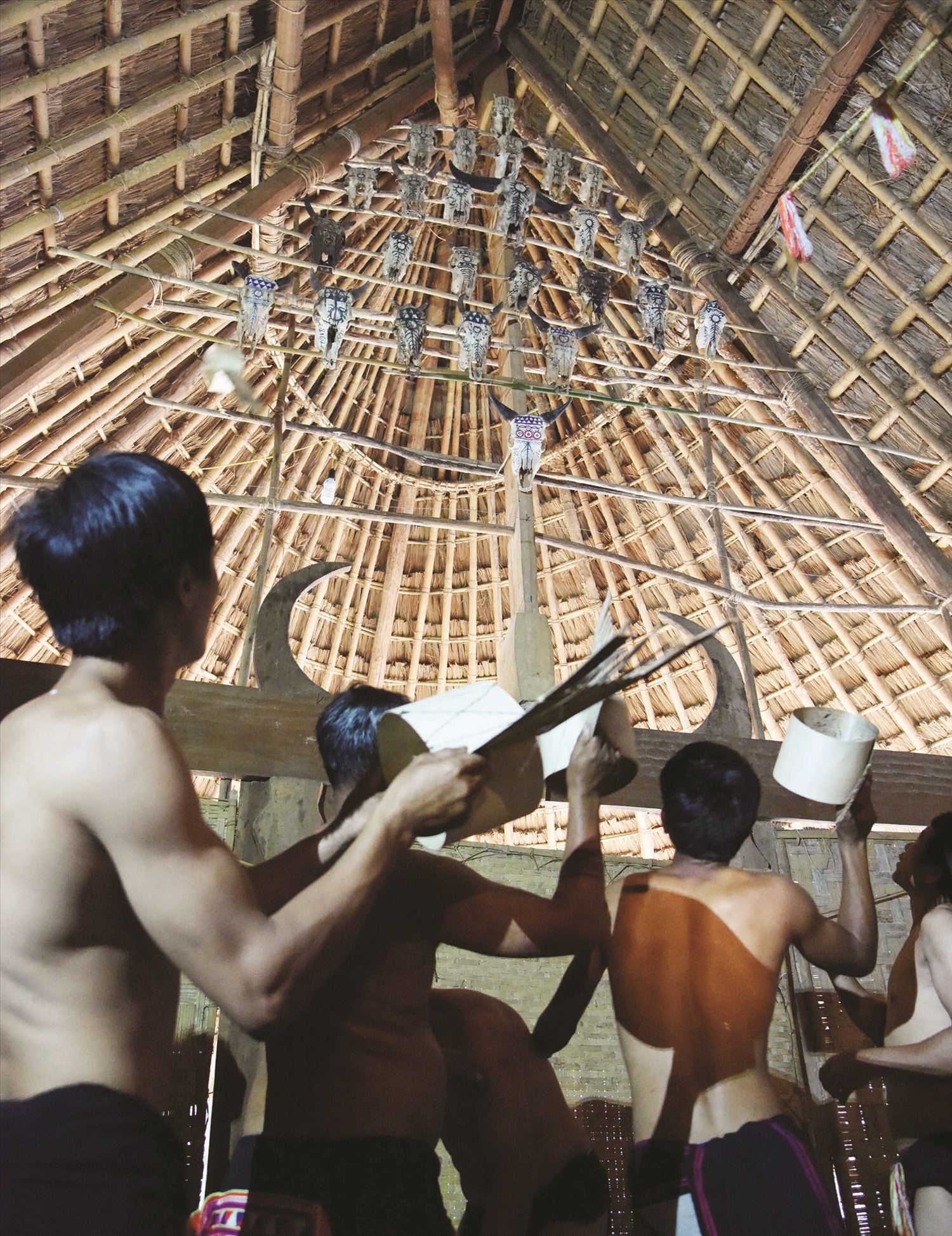 Những người ăn than ném chiếc mũ hình chim lên nơi đặt các sọ thú trong nhà làng để mong những lời cầu khấn được linh ứng Những người ăn than ném chiếc mũ hình chim lên nơi đặt các sọ thú trong nhà làng để mong những lời cầu khấn được linh ứng