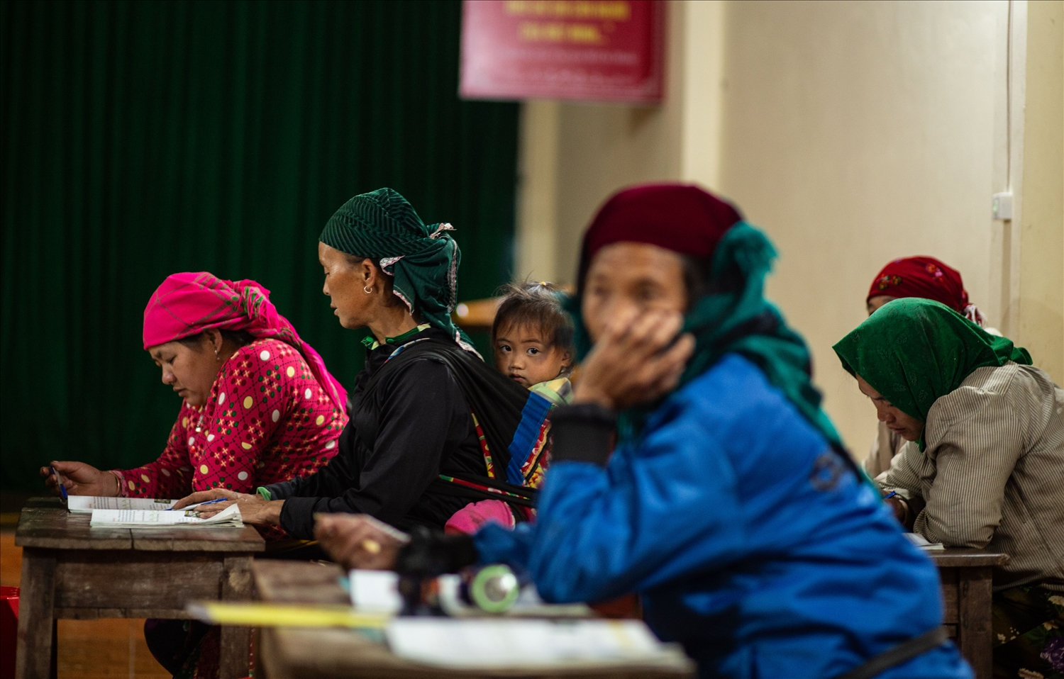 Tại lớp học cũng có những học viên lớn tuổi, các con đều đi làm ăn xa đành phải gửi lại cháu cho ông bà, thế nên cũng có khi bà địu cháu đến lớp, cháu xem bà đánh vần