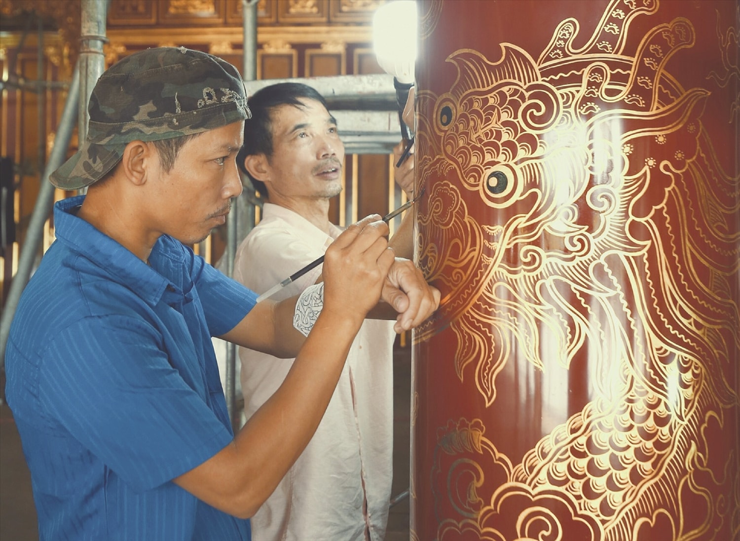 Một nghệ nhân đang tỉ mỉ khắc họa hình tượng linh vật rồng  lên một trụ cột bên trong điện Thái Hòa. 