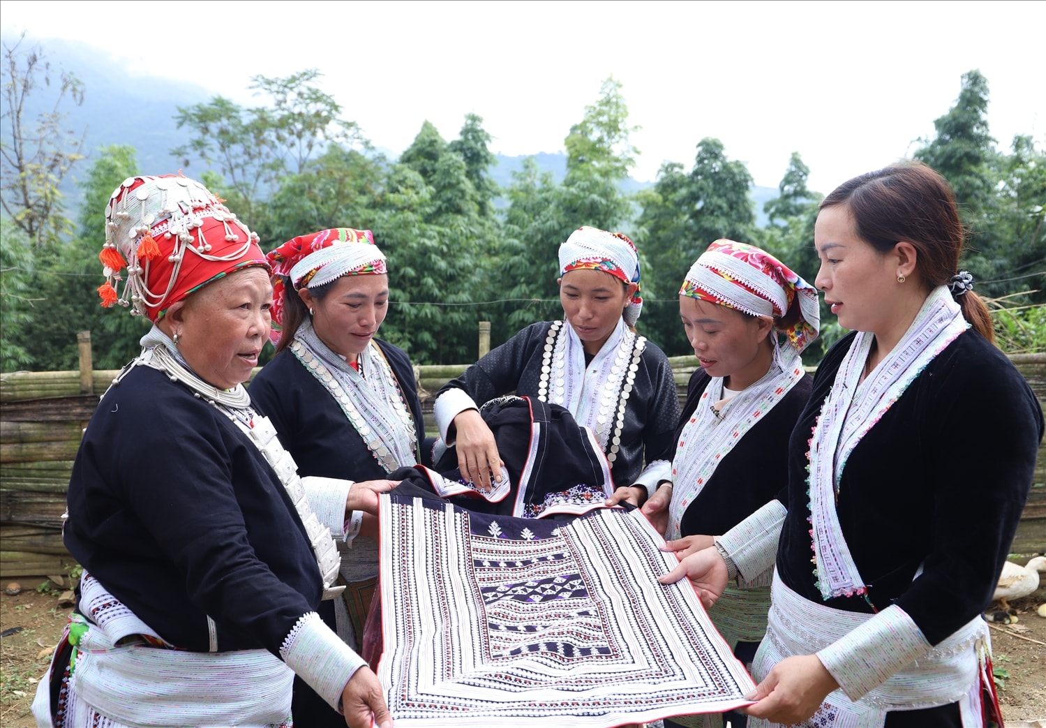 Nghệ nhân dân gian Tẩn Thị Mẩy (ngoài cùng bên trái) và chị em người Dao ở thôn Dền Sáng xem lại sản phẩm thổ cẩm do chính chị em thêu dệt nên. 