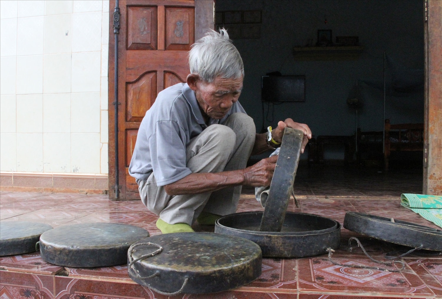 Nghệ nhân Y Krai Cil cẩn thận lau từng chiếc cồng chiêng Nghệ nhân Y Krai Cil cẩn thận lau từng chiếc cồng chiêng