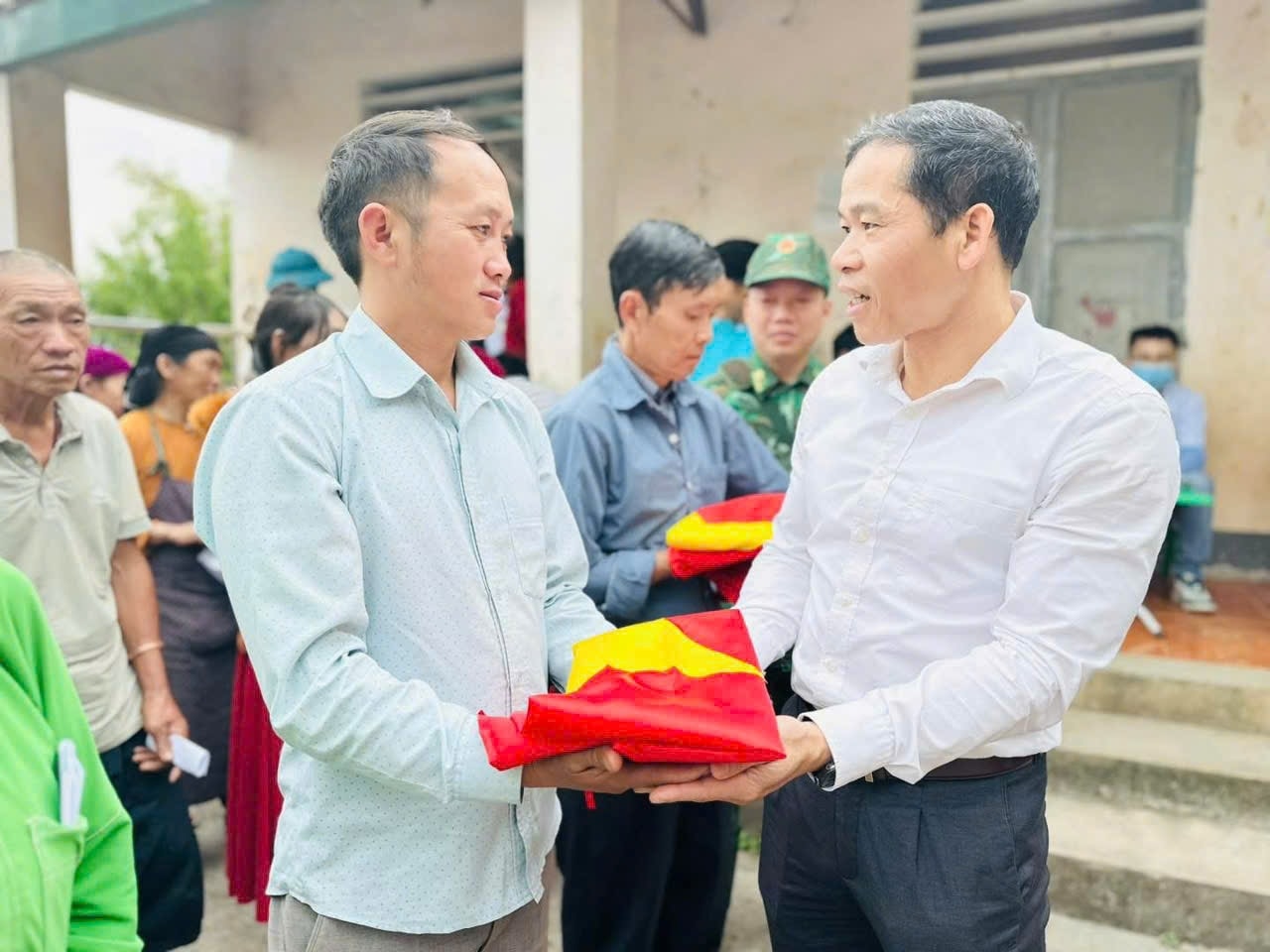 Ông Dương Ngọc Đức, Bí thư Đảng ủy thị trấn Đồng Văn (áo trắng) tặng cờ Tổ quốc cho các hộ  dân biên giới thôn Mã Pắng, thị trấn Đồng Văn (Hà Giang)