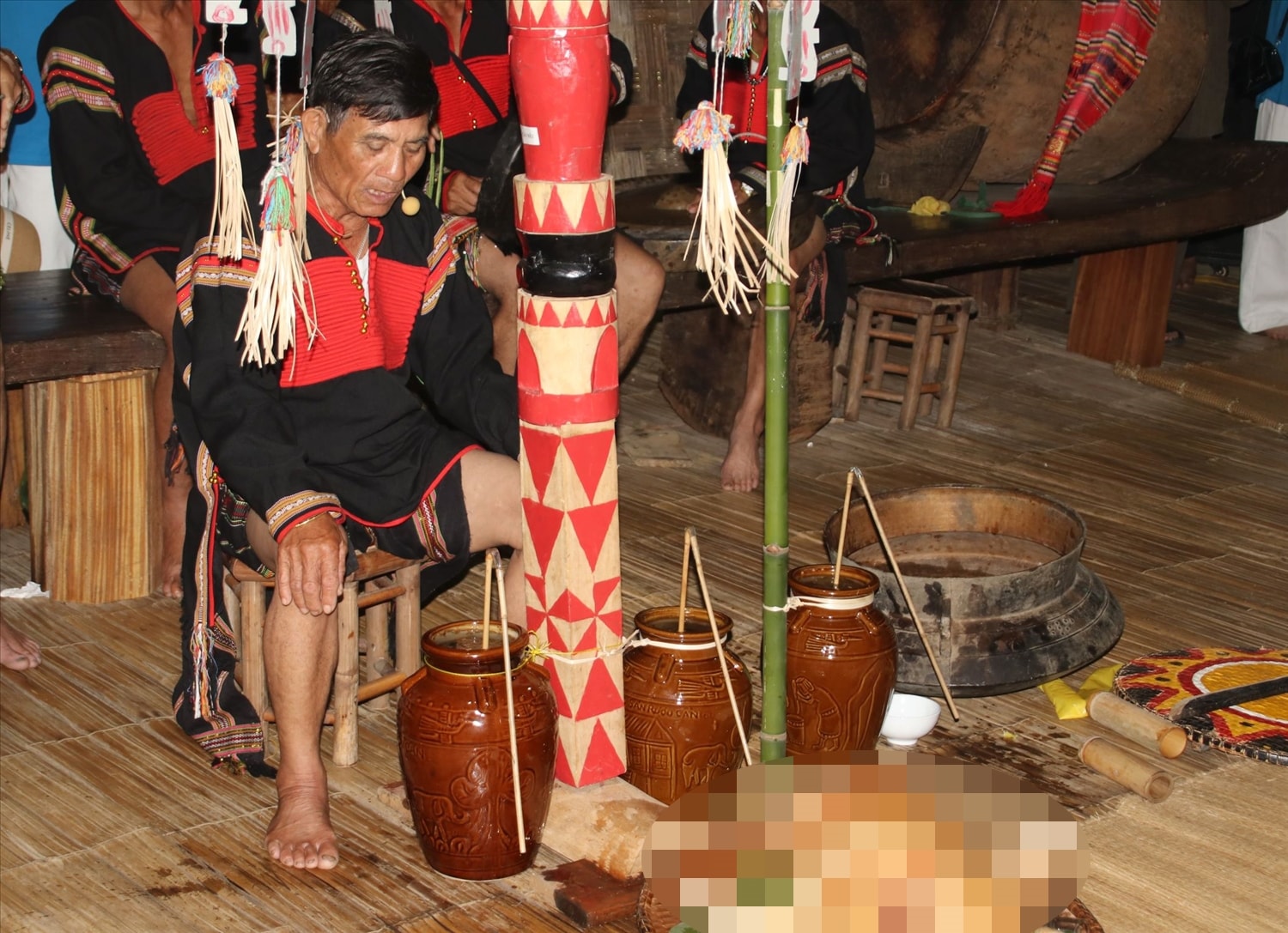 Thầy cúng sẽ ngồi vào vị trí và châm nước vào 3 ché rượu Thầy cúng sẽ ngồi vào vị trí và châm nước vào 3 ché rượu
